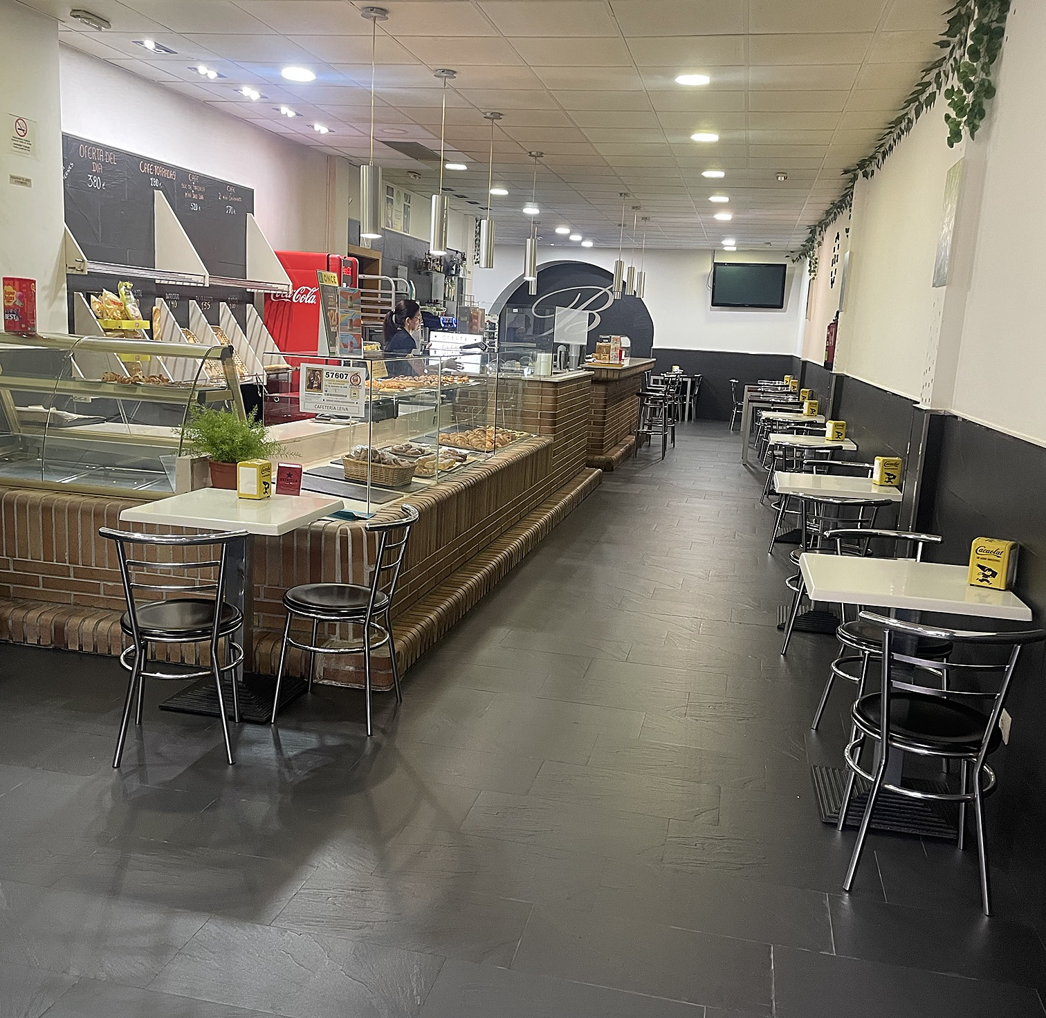 Salón de la cafetería con mesas a lo largo y la barra de ladrillo